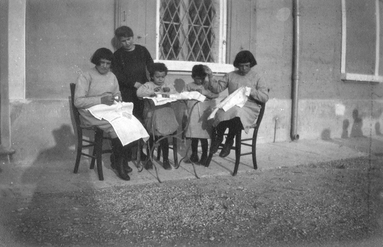 Un gruppo di bambine che ricamano all’esterno della struttura, dicembre 1921 (Archivio del San Lazzaro, Reggio Emilia)